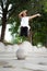 Outdoor portrait of a cute Malaysian little girl with long hair jumping from the concrete ball in the park