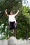 Outdoor portrait of a cute Malaysian little girl with long hair jumping from the concrete ball in the park