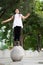 Outdoor portrait of a cute Malaysian little girl with long hair jumping from the concrete ball in the park