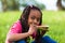 Outdoor portrait of a cute young black little girl eating watermelon - African people