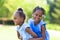 Outdoor portrait of a cute young black sisters - African people