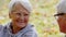 outdoor portrait of an elderly pensioner lady talking with her husband in a park