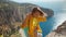 Outdoor portrait of happy smiling girl hiker climbing up on cliff and holding helping hand for reaching to summit cliff