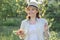 Outdoor portrait of happy woman 40 years old, female in garden in straw hat with plate of strawberries mint lemon