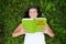 Outdoor portrait of a happy young woman reading a cookbook