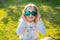 Outdoor portrait of a little blonde smiling toothless girl wearing heart-shaped sunglasses, sitting on fresh green grass. Party