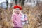 Outdoor portrait of little cute toddler girl in pink coat and red fashion hat barret playing with soft plush dog toy