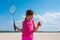 Outdoor portrait of a little girl with racket and shuttlecock in his hands by the river in Sunny day. Beach badminton, Concept