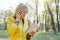 Outdoor portrait of mature business woman with glasses reading book talking on the phone. Female blonde in yellow raincoat,