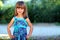 Outdoor portrait of optimistic smiling pretty little girl in blu