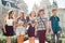 Outdoor portrait of school teacher with bouquet of flowers and group of teenage school children. Children congratulate their