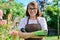 Outdoor portrait smiling female gardener looking at camera in backyard