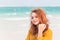Outdoor portrait of smiling red haired teenage girl on the beach
