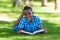 Outdoor portrait of student black boy reading a book