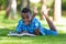 Outdoor portrait of student black boy reading a book