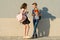 Outdoor portrait of teenagers, boy with bouquet of flowers and girl, gray wall background