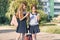 Outdoor portrait of two little schoolgirls with backpacks in school uniforms, smiling and eating ice cream