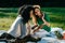 Outdoor portrait of two multi-race happy girl friends watching something on the mobile phone uring their picnic on the