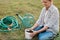 Outdoor portrait of young adult careful woman planting a young raspberry plant, female holding raspberry seedling for planting in