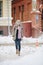 Outdoor portrait of young beautiful happy girl posing on street. Model wearing stylish warm clothes. Magic snowfall. Winter holida