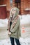 Outdoor portrait of young beautiful happy girl posing on street. Model wearing stylish warm clothes. Magic snowfall. Winter holida
