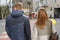 Outdoor portrait of young couple walking on city street, happy young man and woman on zebra crossing, back view, urban background