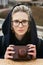 Outdoor portrait of young hipster woman in autumnal cold city park. woman holds retro camera in leather case