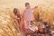 Outdoor shot of beautiful woman with her little doughter toddler wearing pink dress and tights in wheat field on summer day, mommy