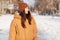 Outdoor shot of brunette young woman focused aside, enjoys winter moments and stroll in open air, dressed in brown stylish