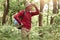 Outdoor shot of expert explorer in forest looking away and keeping hands near forehead, trying to find way, surrounded with green