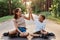 Outdoor shot of happy family mother and son wearing casual style clothing and roller skates sitting on asphalt road in park, boy