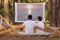 Outdoor shot of lovely couple sitting in the forest with overhead projector, watching movie or photos from vacation, hugging each