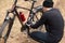 Outdoor shot of man repairing his icycle in field or forest, having puncture of bicycle camera on way, guy posing backwards,