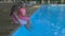 Outdoor shot of two little girls dipping their feet in the pool. Cute little girls sitting on the edge of a swimming