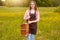 Outdoor shot of young chjarming woman artist standing in meadow, holding sketchbook, ready to paint picture in nature in summer,