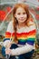 Outdoor spring portrait of adorable redheaded kid girl holding transparent umbrella