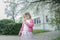 Outdoor spring portrait of preschooler girl looking at little pocket mirror in spring yard