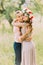 Outdoor spring portrait of young romantic hipster couple hugs posing, in the city garden around blooming trees and flowers