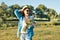 Outdoor summer portrait of adult woman with bouquet of wildflowers, straw hat and sunglasses. Nature background, rural landscape,