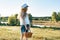 Outdoor summer portrait of little girl with basket strawberries, straw hat. Nature background, rural landscape, green meadow,