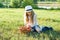 Outdoor summer portrait of little girl with basket strawberries, straw hat. Nature background, rural landscape, green meadow, coun