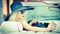 Outdoor summer portrait of stylish blonde vintage woman driving a convertible red retro car. Fashionable attractive fair hair girl