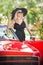 Outdoor summer portrait of stylish blonde vintage woman posing near red retro car. fashionable attractive fair hair female