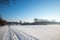 Outdoor sunny view of thick layer snow cover street, land and field in countryside.