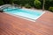 Outdoor swimming pool with cover enclosure and teak wood deck, exotic teakwood flooring stripes around blue water pool