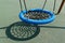 Outdoor swing with wicker round seat on green artificial ground