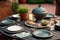 outdoor table with ceramic dishes and food next to barbecue backyard grill