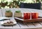 Outdoor table setting with cookies, two red coffee cups, book, flowers
