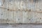 An outdoor thick rough gray concrete wall with part of floor surface, visible imprints of wooden planks