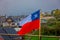 Outdoor view of Chilean flag waving with beautiful and colorful houses on stilts palafitos behind in the horizont in